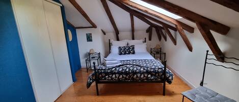 A bedroom with a bed, a nightstand, a lamp, and a bench.