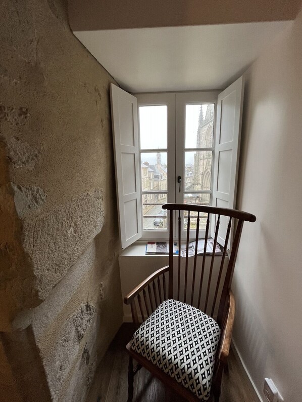 A corner room with a wooden chair, a window with a view of a building, and a white door. - amazing view next to the cathedral in the historic heart of the city (Vannes)