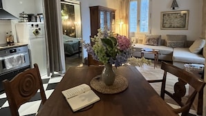 A dining area with a wooden table, chairs, a vase with flowers, and a book.