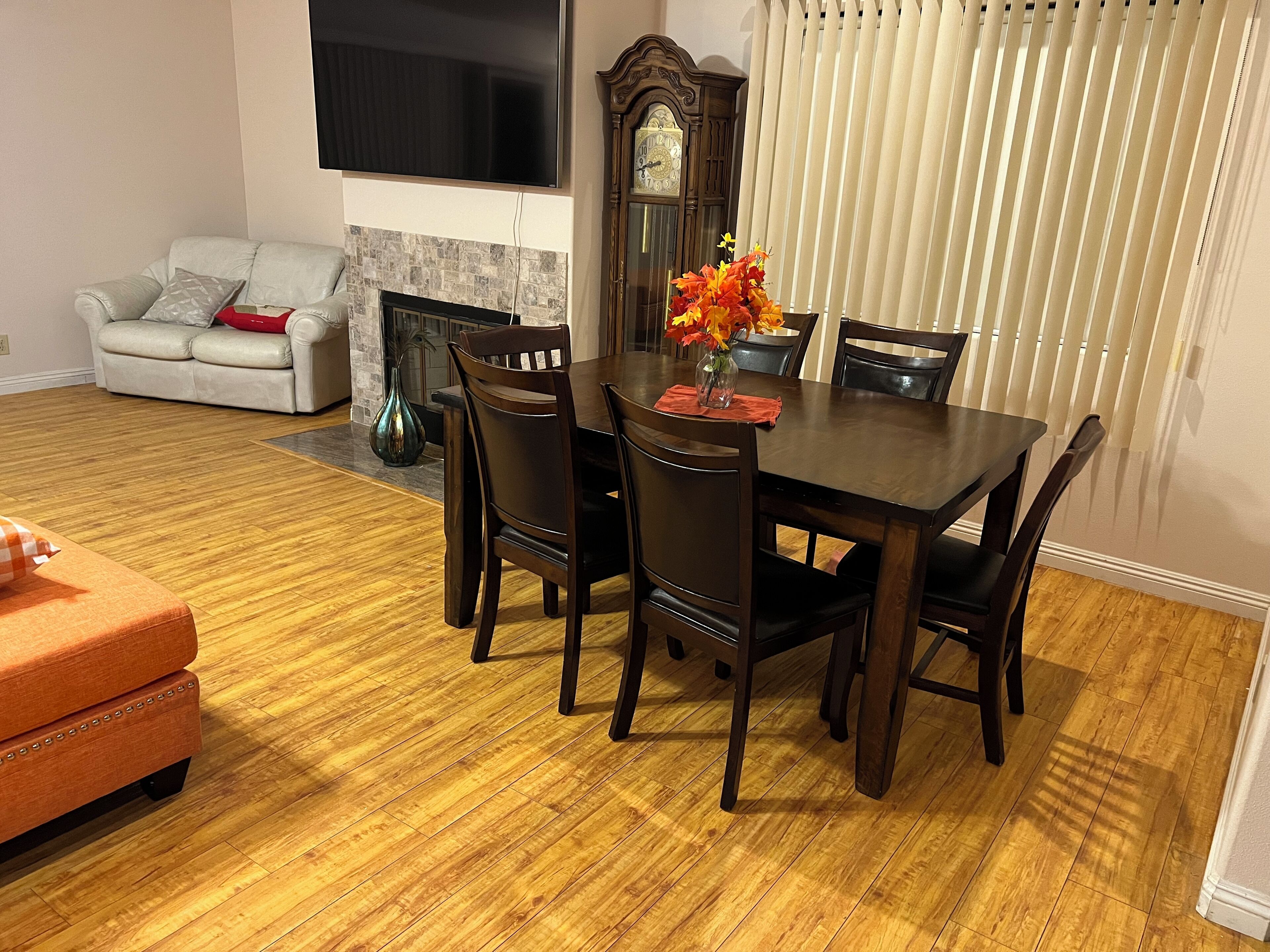 Un coin repas avec une table en bois, six chaises et un vase de fleurs.