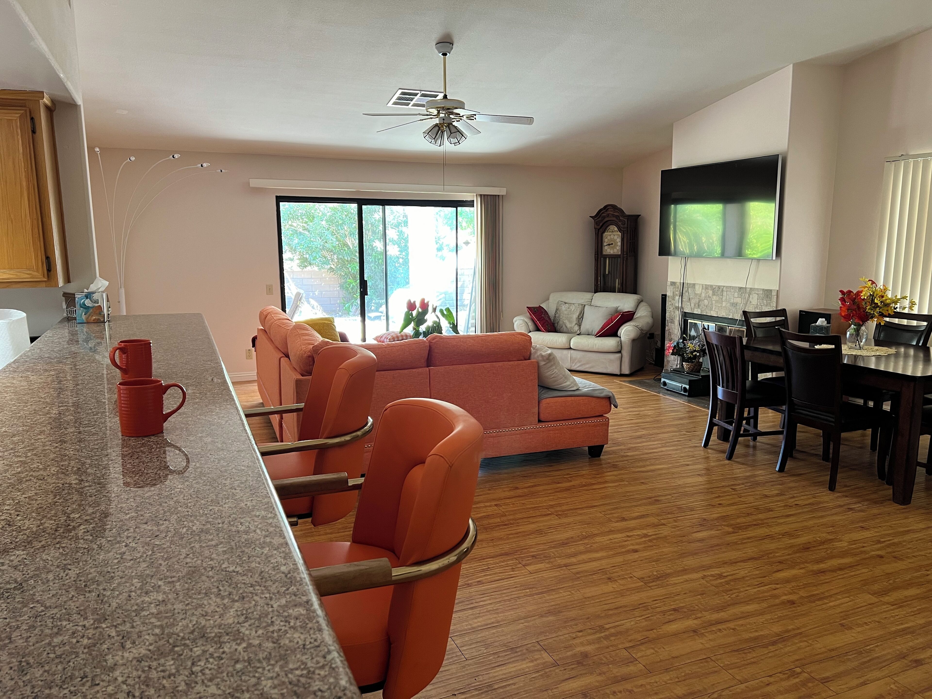 Amplia sala de estar con un ventanal grande, comedor con mesa de madera y cocina con encimera de granito.