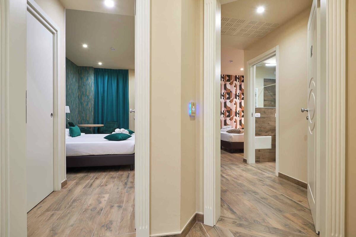 A hotel room with a bed, a desk, and a bathroom visible through an open door.