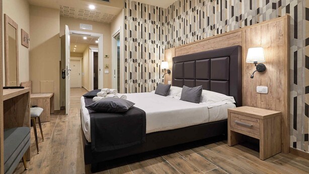 A modern bedroom with a large bed, bedside tables, and a wooden wardrobe.
