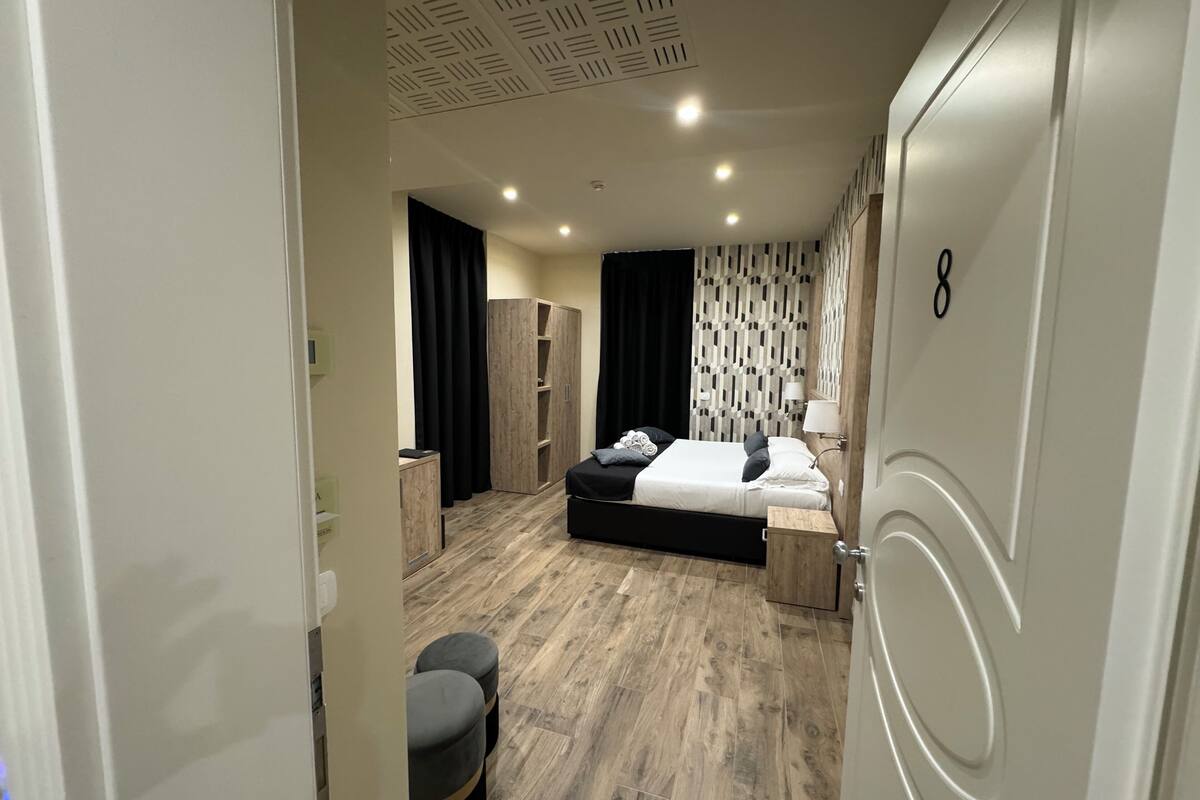 A modern bedroom with a large bed, a wardrobe, a desk, and a chair.