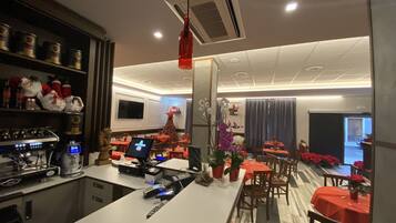 Un restaurante con área de bar, mesas con manteles rojos y un árbol de Navidad.