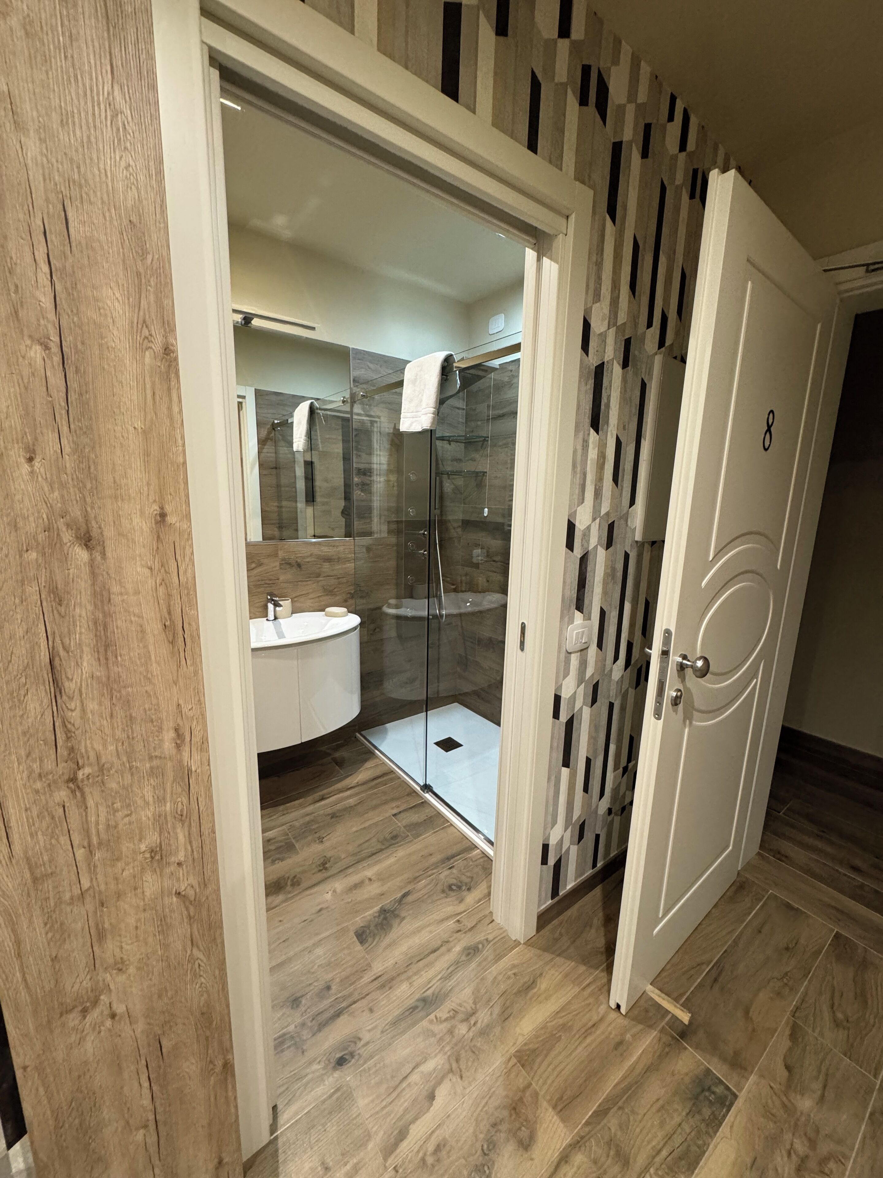 A modern bathroom with a glass-enclosed shower, a white sink, and a vanity.