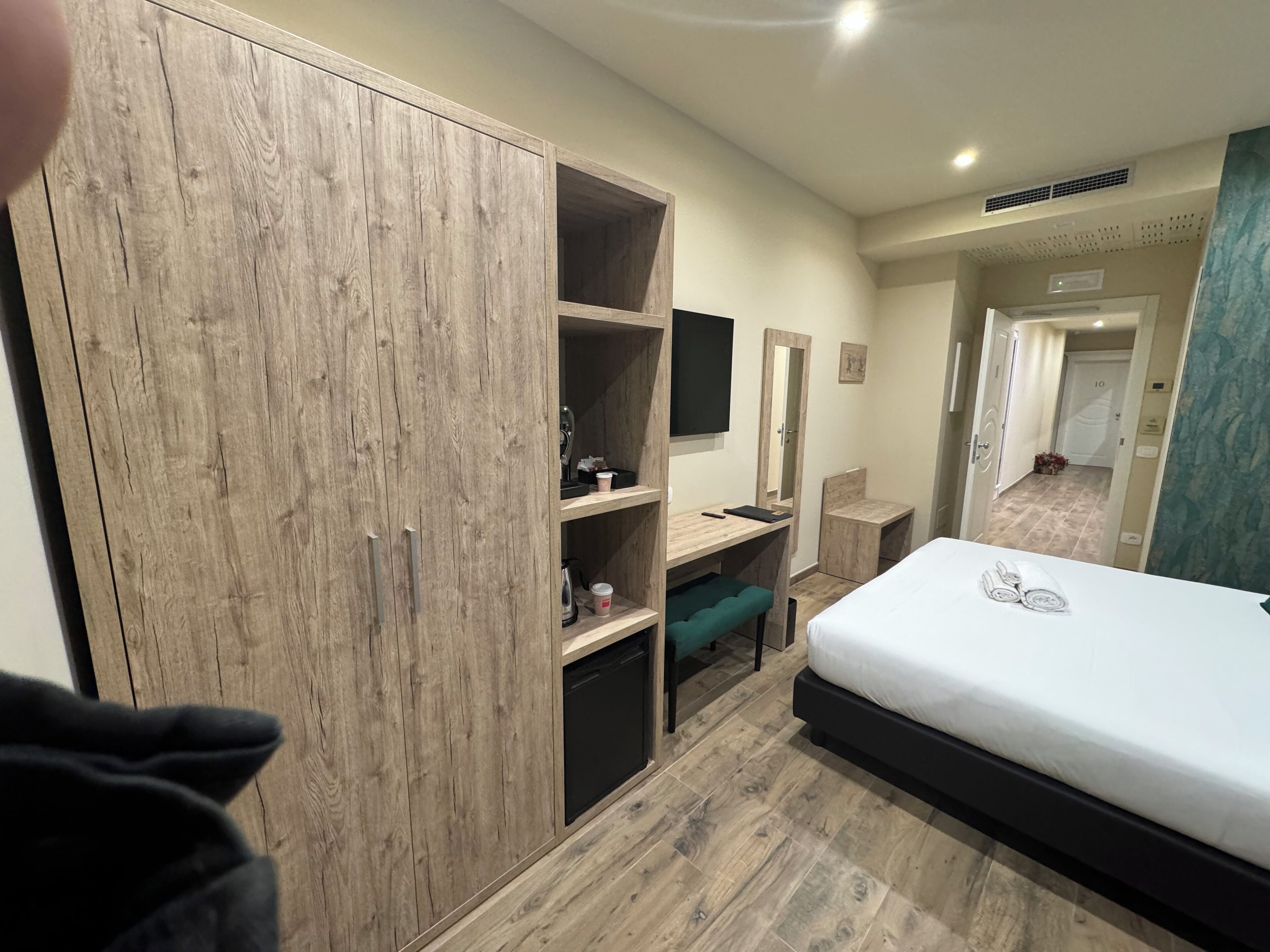 Een slaapkamer met een houten garderobe, een bureau met stoel, een bed en een spiegel.