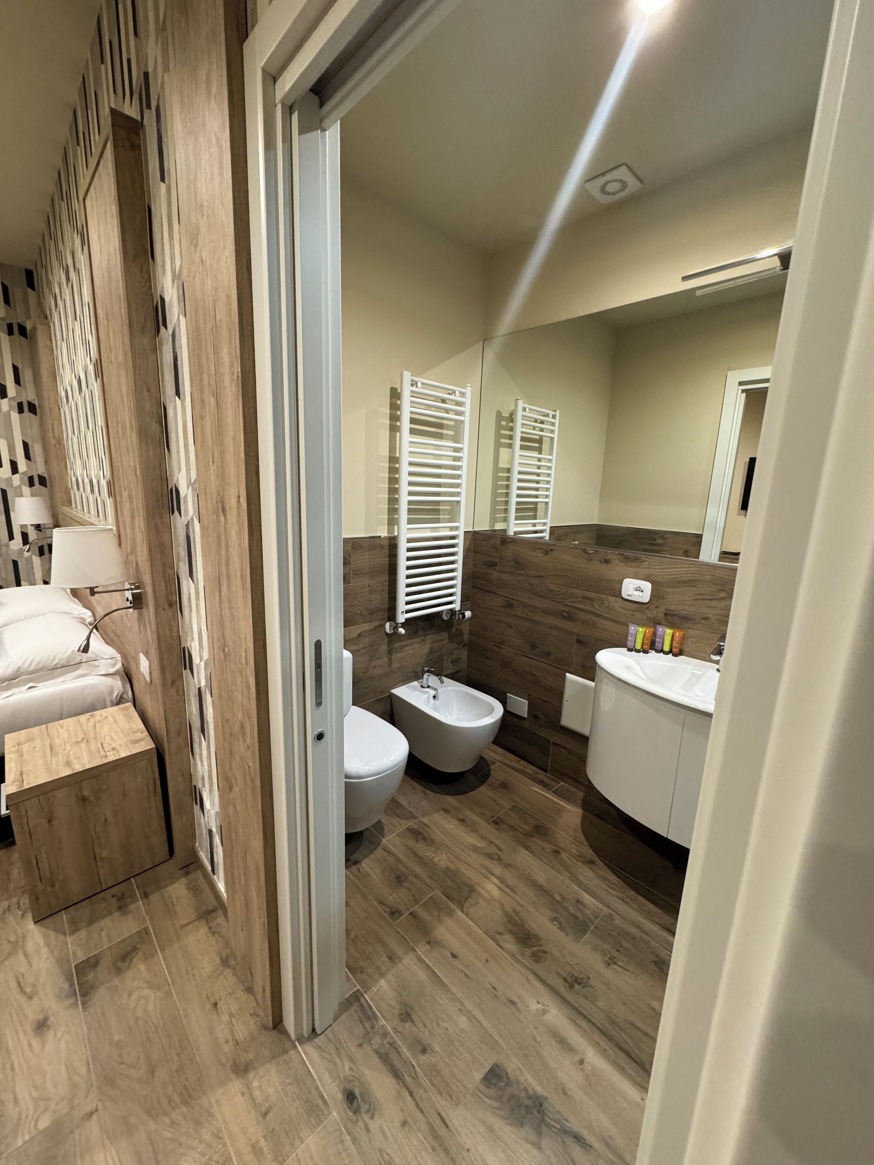 A modern bathroom with a wooden floor, a toilet, bidet, and a vanity with a sink.