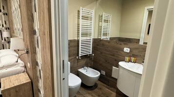 A modern bathroom with a wooden floor, a toilet, bidet, and a vanity with a sink.