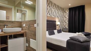 A modern hotel room with a wooden vanity, a large bed with dark headboard, and a patterned wall.
