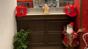 A bathroom with a mirror, a sink, and a decorative Santa Claus figure.