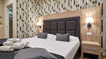 Ein modernes Hotelzimmer mit einem großen Bett, zwei Nachttischen und einer Wand mit geometrischem Muster.