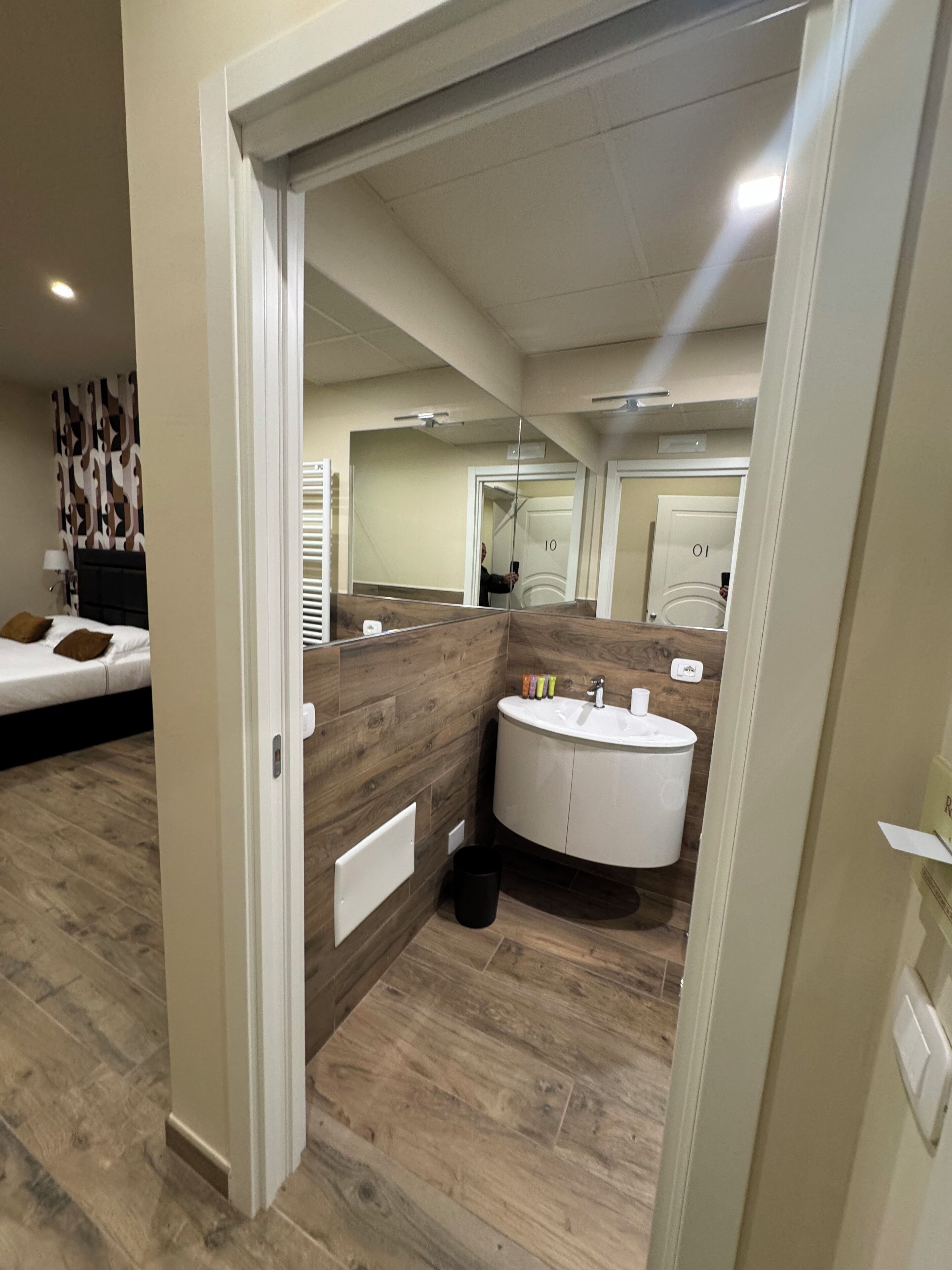 Un baño moderno con tocador de madera, un lavabo redondo y un espejo.