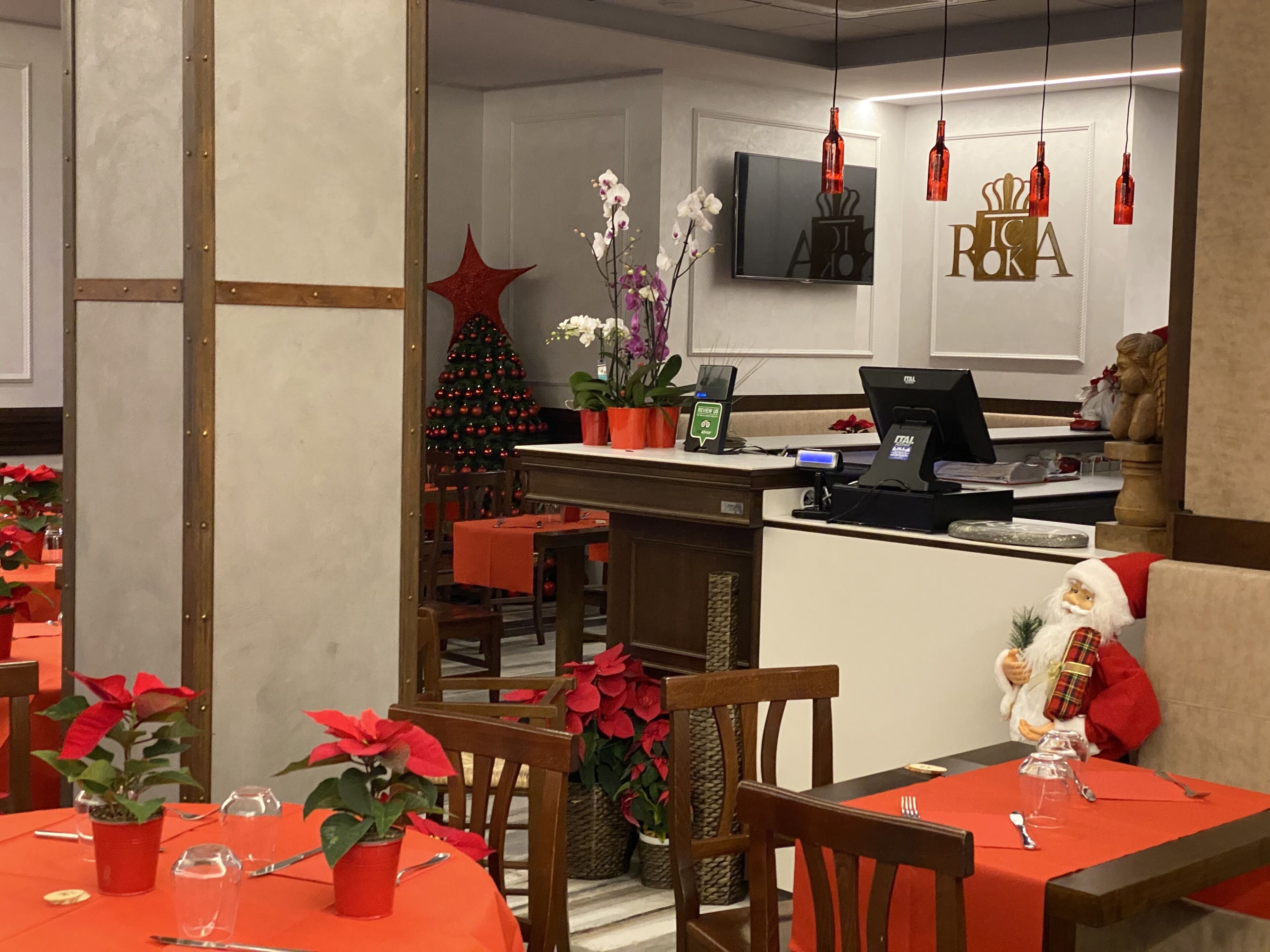 Un ristorante con tavoli apparecchiati per la cena, un albero di Natale e una decorazione con Babbo Natale.