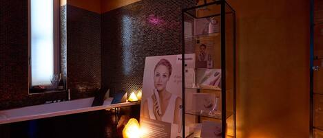 A modern bathroom with a glass shower enclosure, a visible bottle of champagne, and a display of Panasonic products.