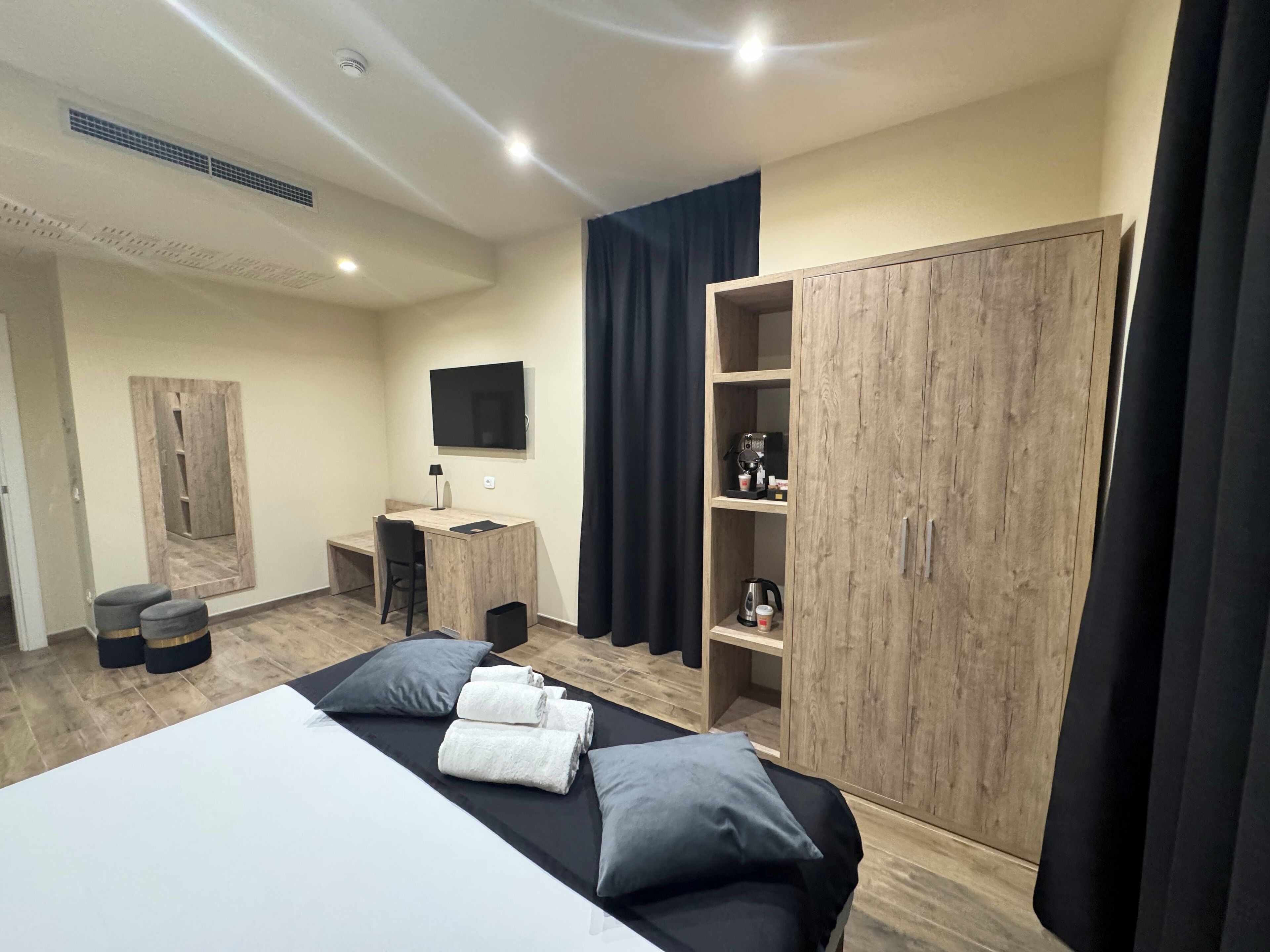A modern bedroom with a bed, a desk, a TV, and a wardrobe.