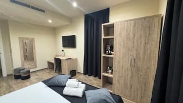 Une chambre moderne avec un lit, un bureau, une télévision et une armoire.