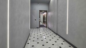 A hallway with a geometric patterned floor, metallic walls, and a door leading to another area.