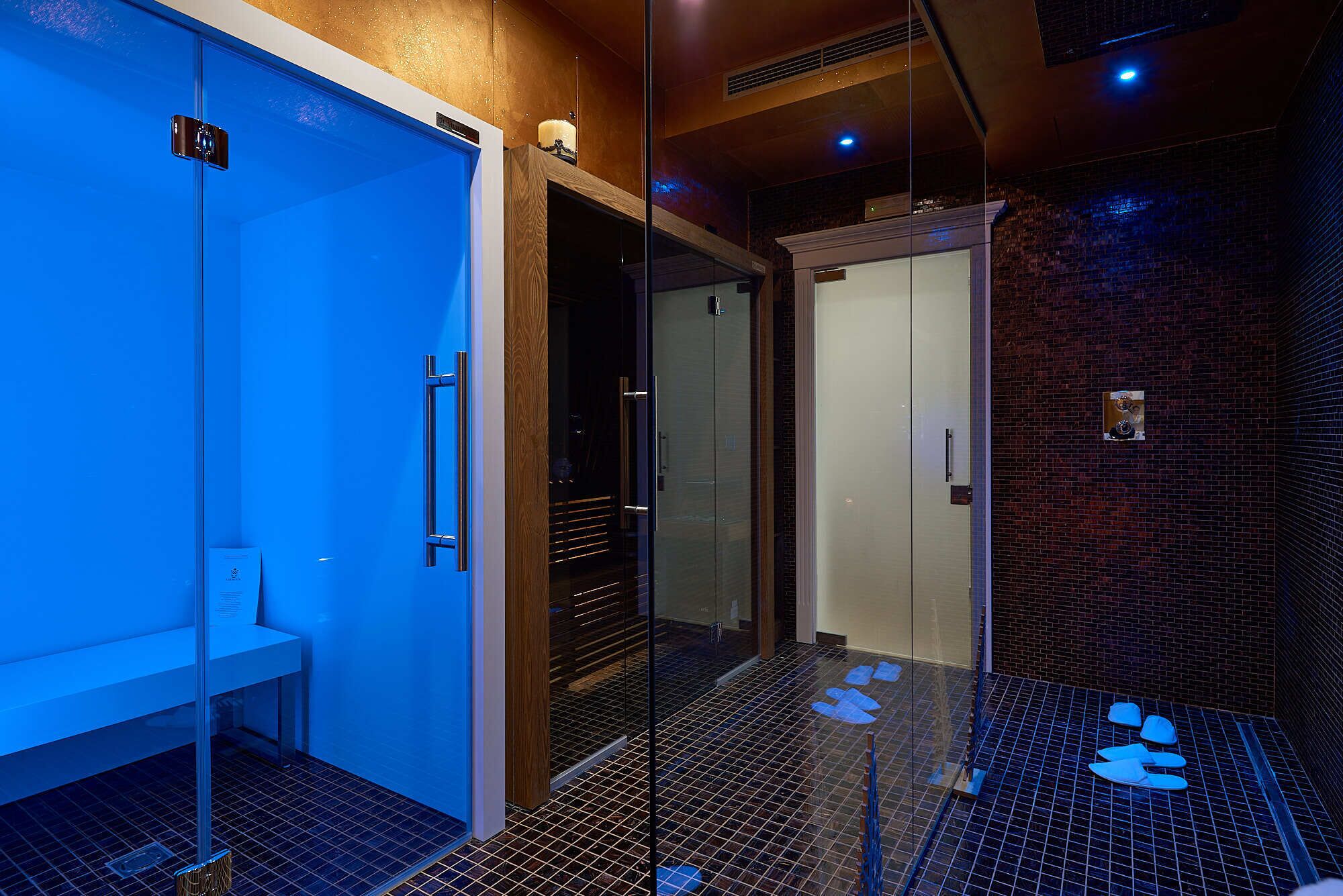 Un baño moderno con mampara de vidrio, un banco y piso de baldosas.