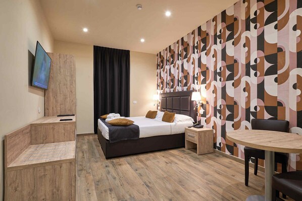 Una habitación de hotel con cama, mesitas de noche, escritorio, silla y mesa de comedor.