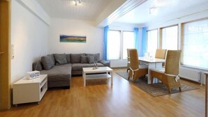 Una sala de estar moderna con un sofá gris, una mesa de centro blanca y sillas de mimbre.
