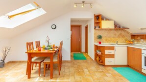 A dining area with a wooden table and chairs, a kitchen with a sink and cabinets, and a skylight above the table. - Apartments Mondo (Dubrovnik)