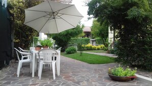 A patio with a stone table and chairs, a large umbrella, and potted plants. - Dimora di Bosco Room & Breakfast (Rubano)