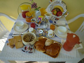 A breakfast table with various food items, including bread, pastries, and a fruit bowl. - Dimora di Bosco Room & Breakfast (Rubano)