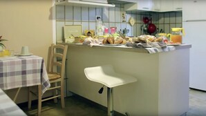 A kitchen with a bar area, a dining table with chairs, and various kitchen items on the counter. - Dimora di Bosco Room & Breakfast (Rubano)