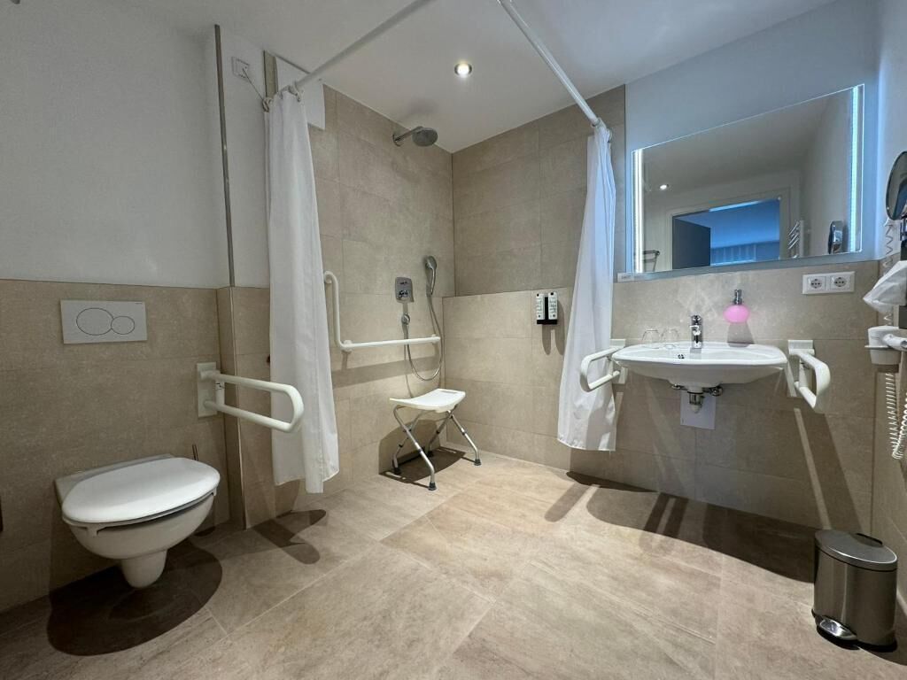 A modern bathroom with a toilet, shower, and sink.