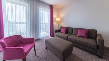 A modern living room with a pink armchair, a brown sofa, and a matching ottoman.