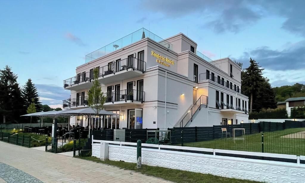 Un hotel moderno con tetto piano, numerosi balconi e una zona salotto esterna coperta.