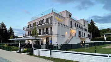Un hotel moderno con tetto piano, numerosi balconi e una zona salotto esterna coperta.