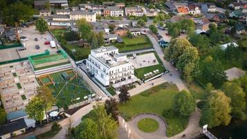 Luchtbeeld van een woongebied met een opvallend wit gebouw, een groen sportveld en een waterpartij.
