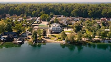 An aerial view of a lakeside town with residential buildings, a central park, and a large white building.