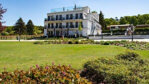 Un hôtel moderne à plusieurs étages, doté d’un toit plat, de grandes fenêtres et d’un jardin bien entretenu à l’avant.