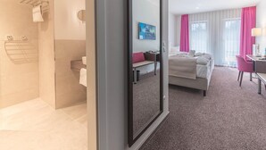 Une chambre d’hôtel moderne équipée d’une douche, d’un lit, d’un bureau et d’une chaise.