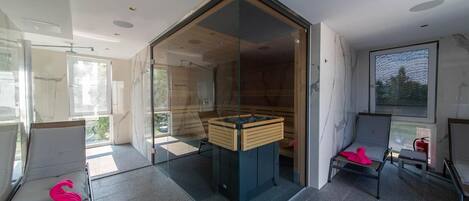 Un baño moderno con mampara de vidrio, banco de madera y vistas al exterior.