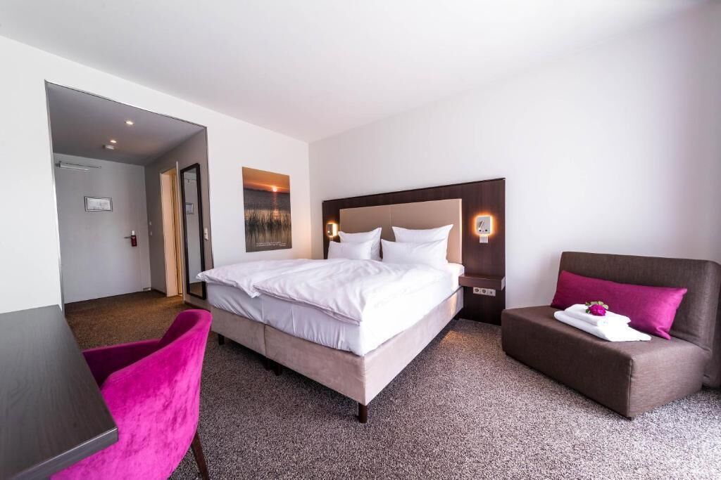 Una camera d'albergo con un letto, una scrivania, una sedia e un divano.