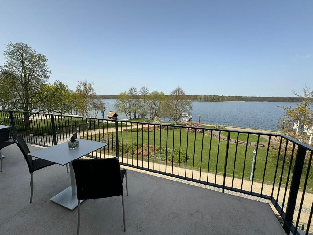 A balcony with a table and chairs overlooking a lake.