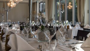 Une table à manger élégante, dressée avec de la verrerie, des couverts et un centre de table agrémenté de fleurs.
