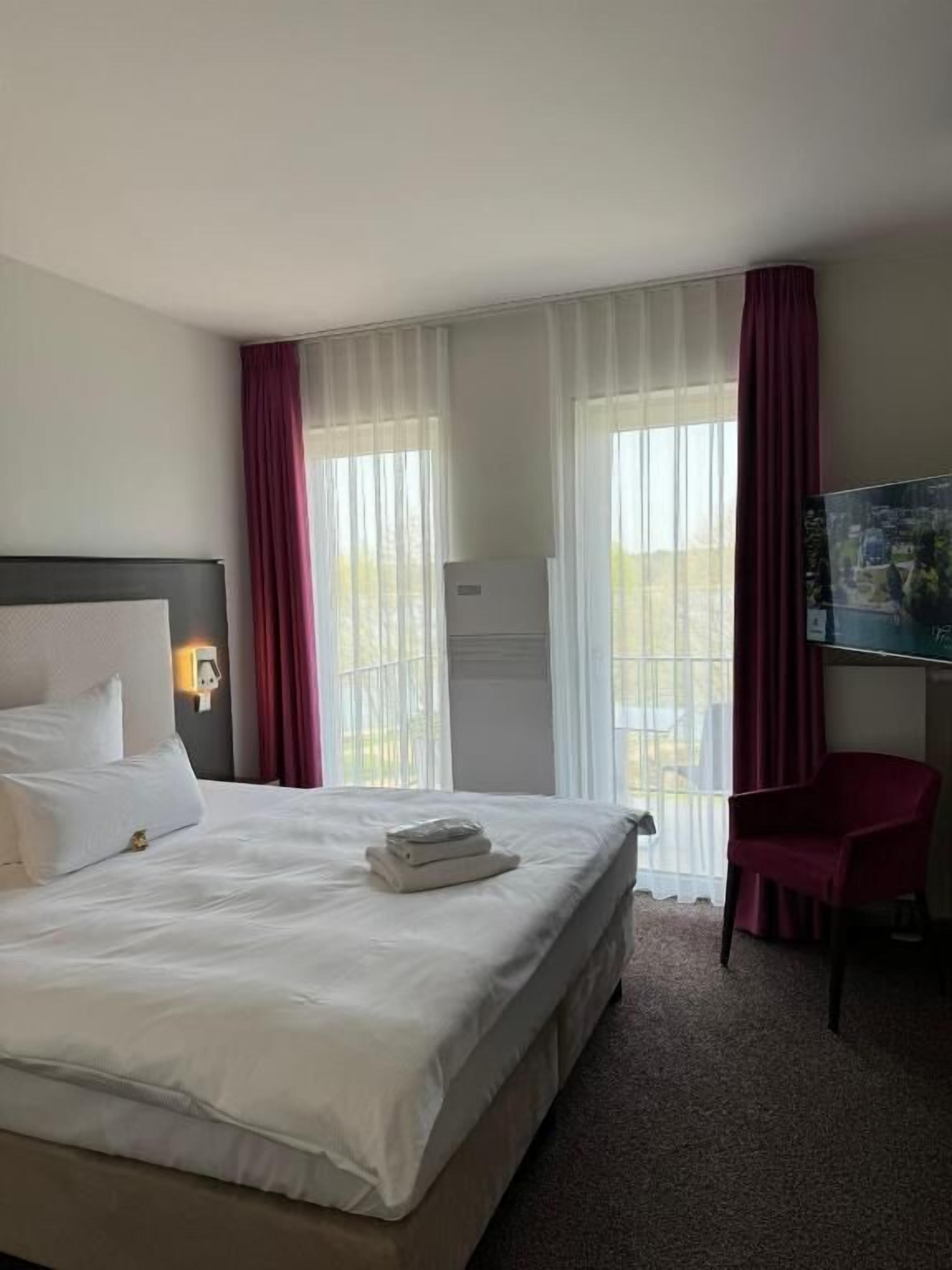 A hotel room with a bed, a desk, and a chair.