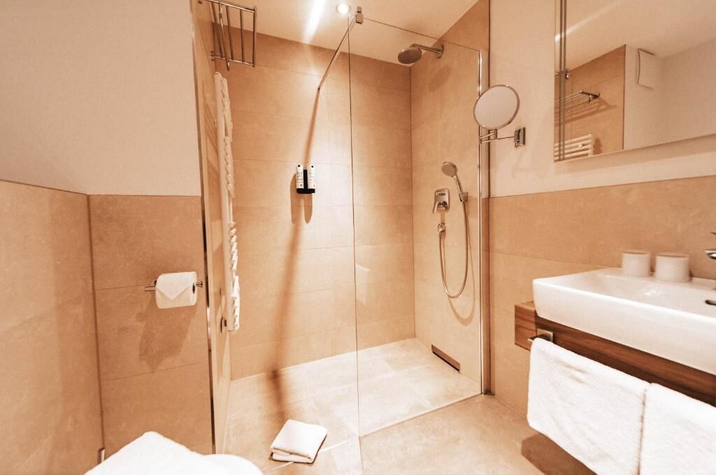 A modern bathroom with a glass-enclosed shower, a large sink, and a mirror above the vanity.