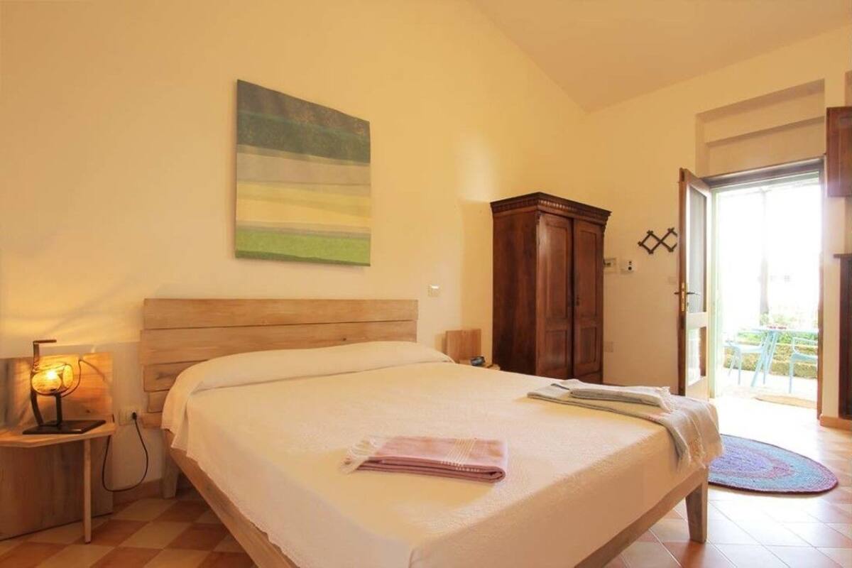 Une chambre à coucher avec un lit, une table de chevet avec une lampe, une armoire en bois et un tableau accroché au mur.