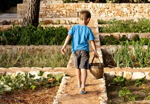 A child walking on a stone pathway in a garden. - Masseria Gianferrante (Ugento)