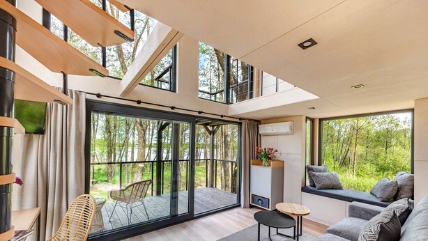 Ein modernes Interieur mit einer großen Schiebeglasäußer zur Terrasse und einer Sofagarnitur sowie einem kleinen Tisch.