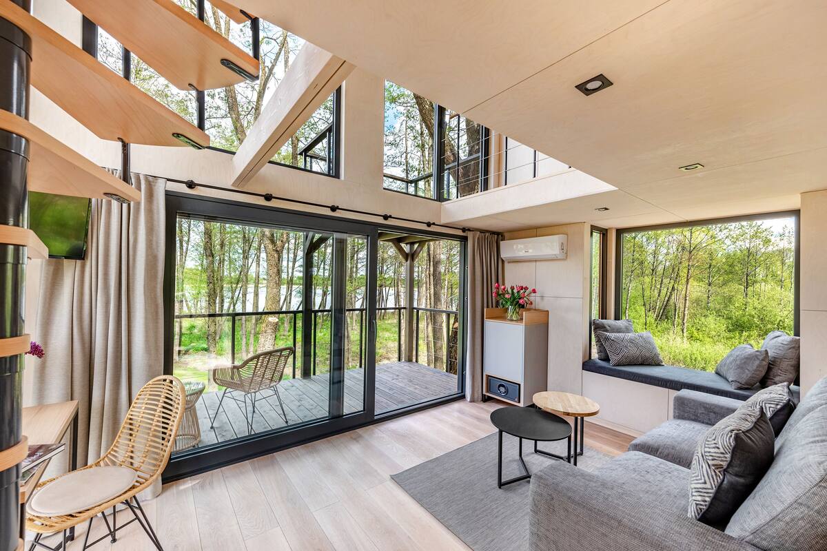 A modern interior with a large sliding glass door leading to an outdoor deck, a sofa set, and a small table.