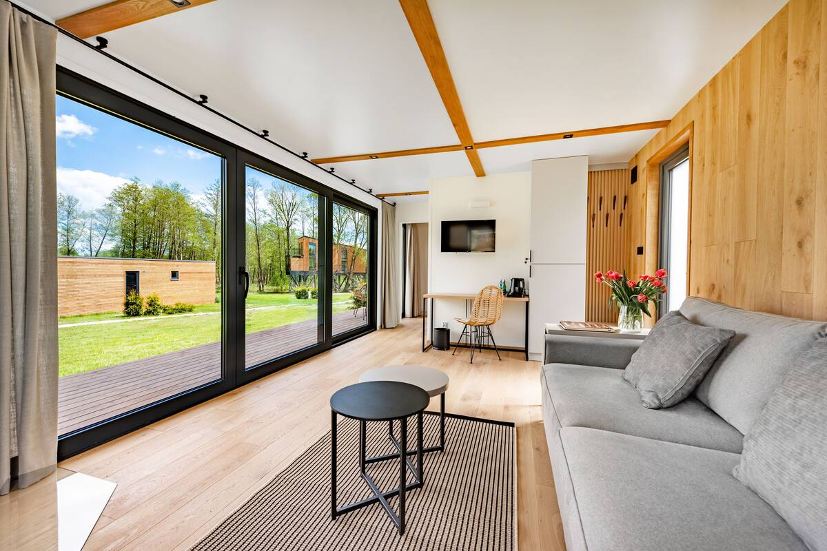 A modern living room with a sofa, a small table, and a TV mounted on the wall.