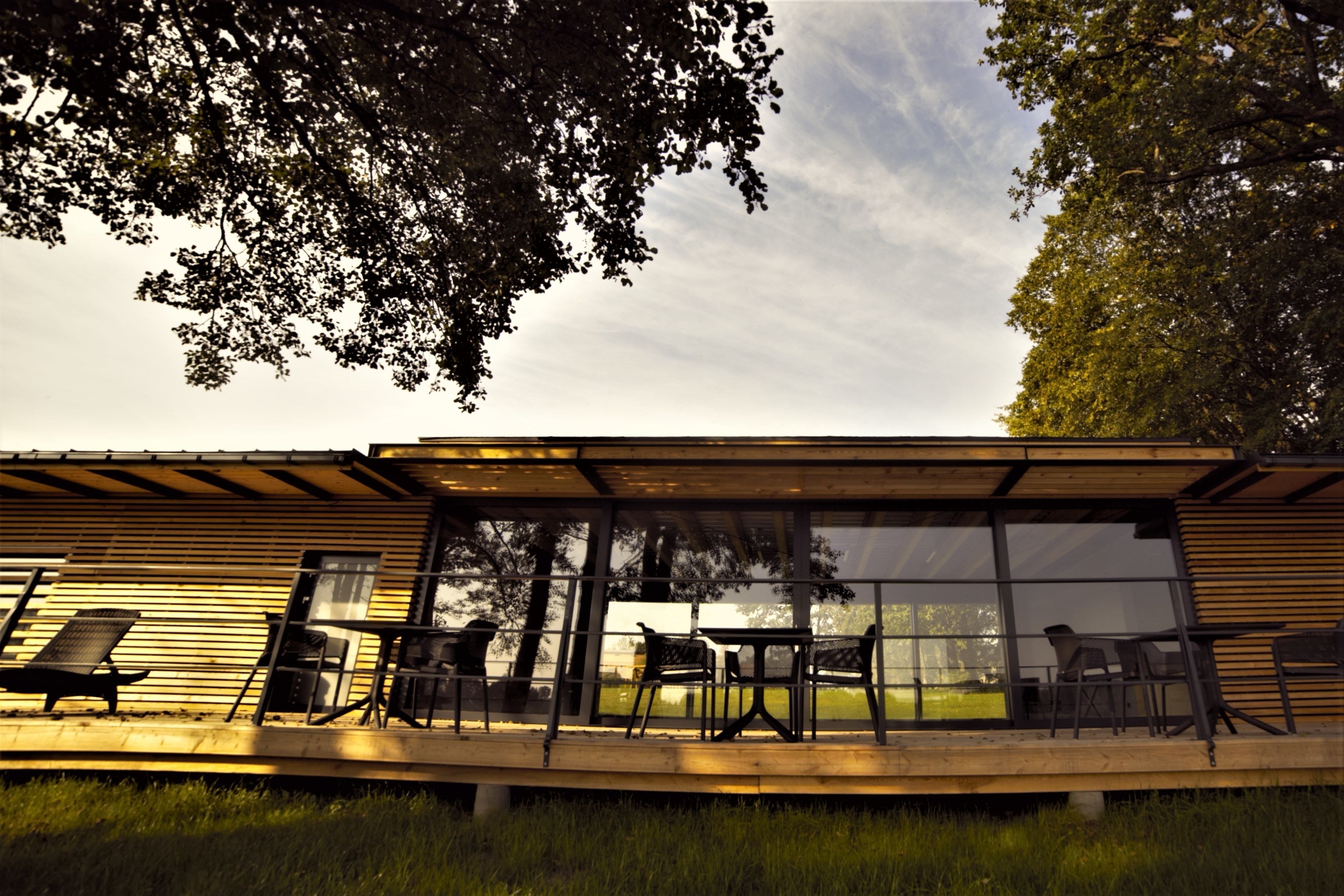 Un espace extérieur moderne, aménagé avec des tables et des chaises, de grandes fenêtres et offrant une vue sur le paysage environnant.