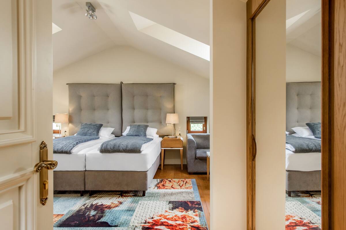 A bedroom with a large bed, bedside tables, a chair, and a skylight.